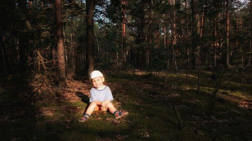 Full length portrait of baby girl sitting in forest