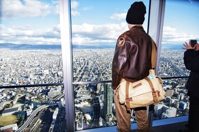 Rear view of man looking through window