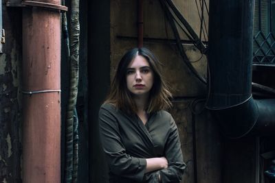 Portrait of young woman standing against wall