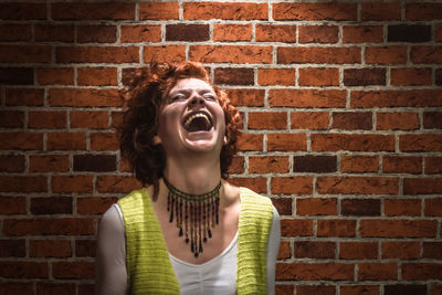 Young woman wearing sunglasses against brick wall