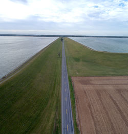 Scenic view of road by sea against sky