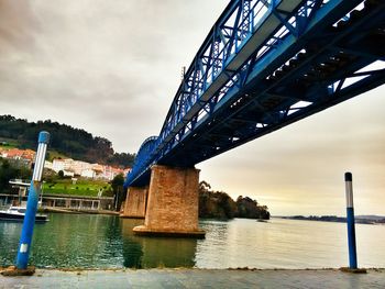 Bridge over river against cloudy sky