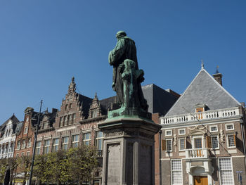 Low angle view of statue against building against clear blue sky