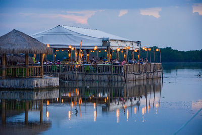 Group of people in restaurant by lake during sunset