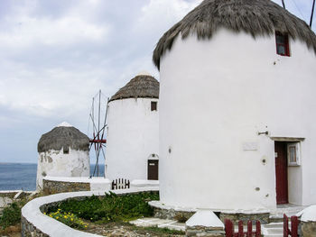 Traditional windmills at mykonos against cloudy sky