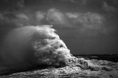 Sea waves rushing towards shore against sky