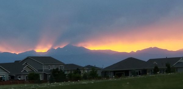 Houses by mountains against sky during sunset