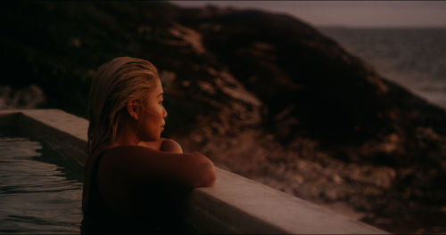 Woman looking away while relaxing in swimming pool