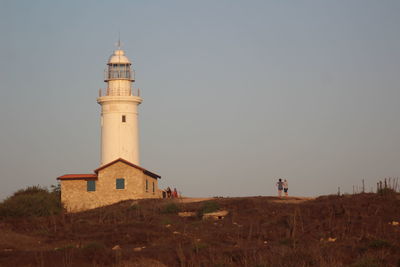 Lighthouse on field against sky