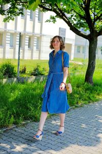 Full length portrait of smiling woman standing on footpath