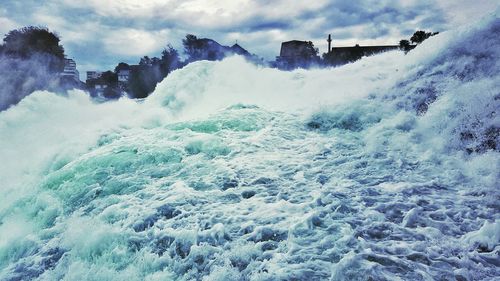 Waves splashing on shore against sky