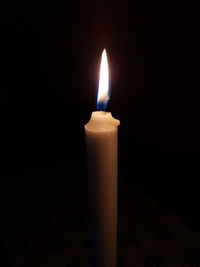 Close-up of illuminated candle in darkroom