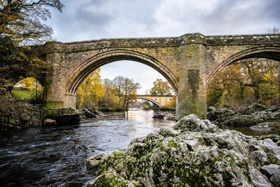 Arch bridge over river against sky