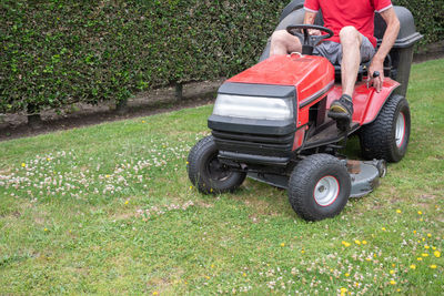 Lawn mower mows the grass, a middle-aged male gardener works on a mini tractor