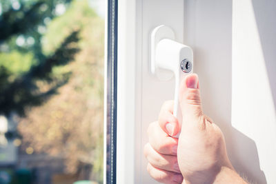 Close-up of hand holding glass door