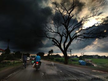 People riding bicycle on road against sky