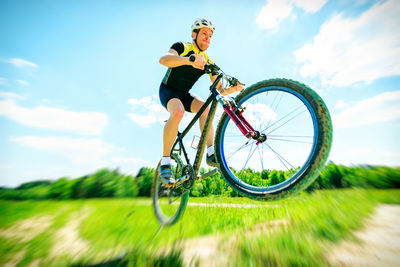 Low angle view of man with bicycle against sky