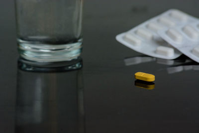 Close-up of medicines and empty glass on table