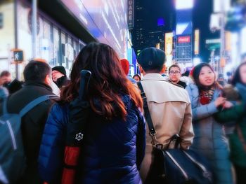 People walking on illuminated street in city