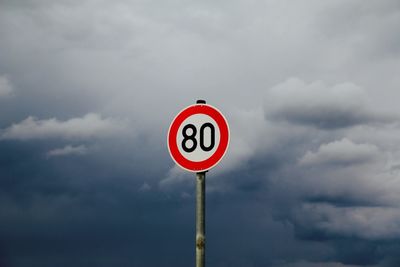 Low angle view of road sign against cloudy sky