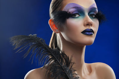 Portrait of young woman against blue background