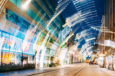 Illuminated street amidst buildings in city at dusk