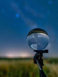 Close-up of light bulb on field against sky