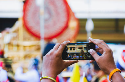 Cropped hand holding smart phone while photographing outdoors