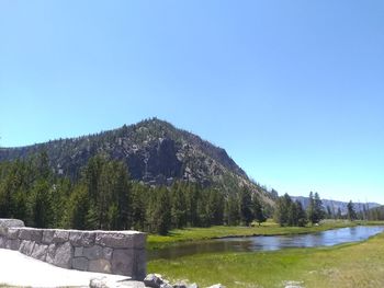 Scenic view of lake and mountains against clear blue sky