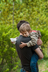 Side view of a boy carrying baby outdoors