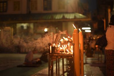 Illuminated candles and incense outside temple at night