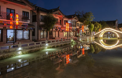 Light trails on street by buildings at night