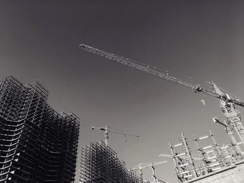 Low angle view of cranes at construction site against clear sky