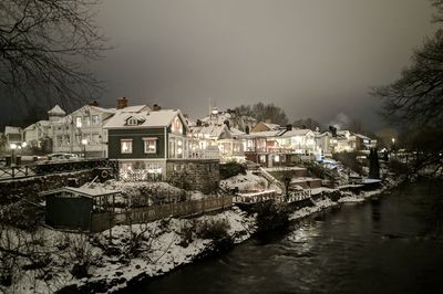 Buildings by river against sky during winter