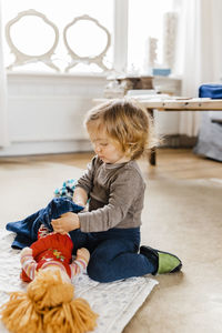 Girl playing with doll on floor at home