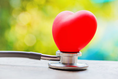 Close-up of red heart shape with stethoscope on table