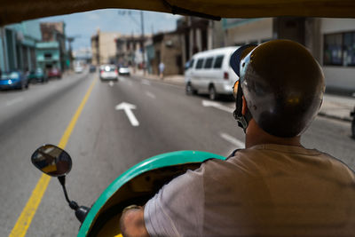 Rear view of man riding motorcycle on street