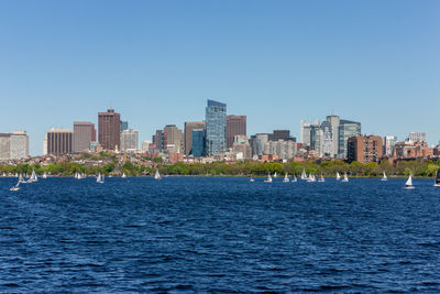 Sea by buildings against clear blue sky