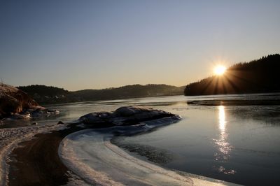 Scenic view of lake against clear sky during sunset