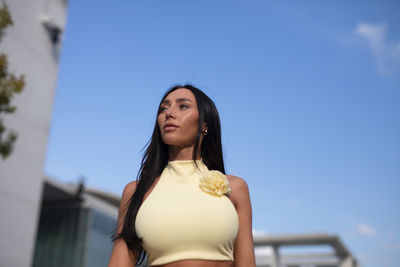 Portrait of young woman standing against sky