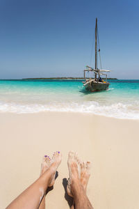 Low section of person on beach against sky