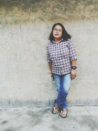 Portrait of smiling young woman standing against wall