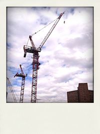Low angle view of crane against cloudy sky