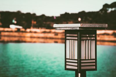 Close-up of signboard on table against lake
