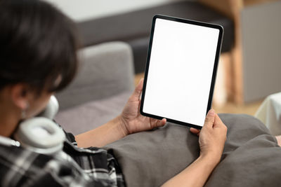 Midsection of woman using digital tablet at home
