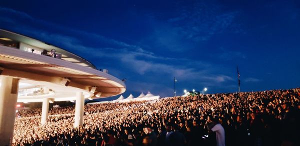 Crowd at music concert against blue sky