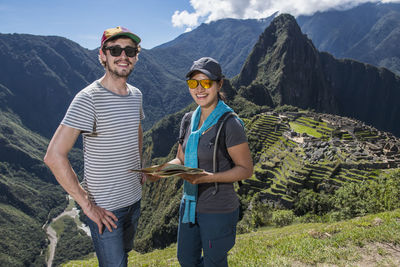 Couple at inca ruins looking at camera smiling, machu picchu, peru