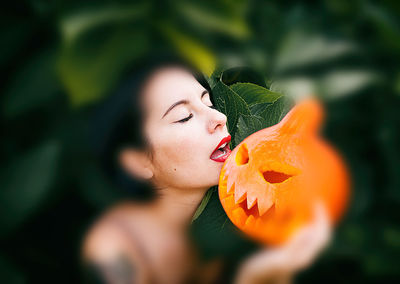 Close-up of woman with pumpkin on leaf