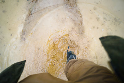 Low section of man walking on muddy field