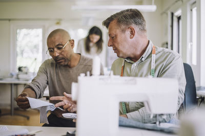 Male design professionals discussing over fabric at workshop